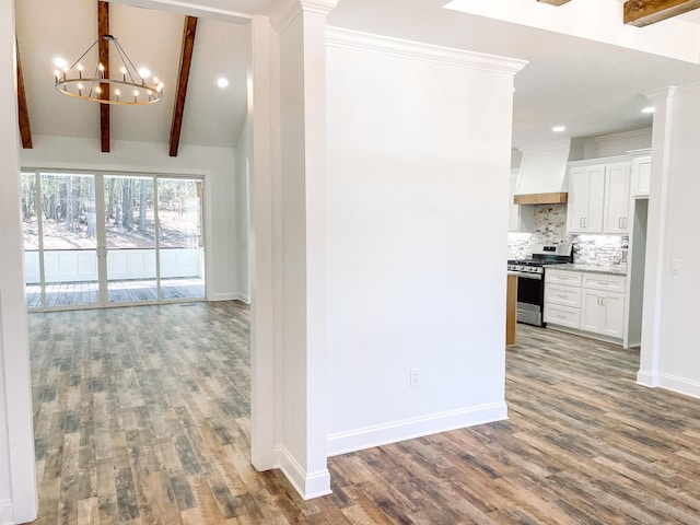 hall with decorative columns, lofted ceiling with beams, wood finished floors, a chandelier, and baseboards