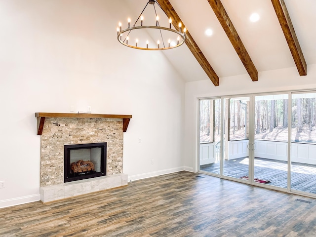 unfurnished living room featuring beam ceiling, a fireplace with raised hearth, baseboards, and wood finished floors