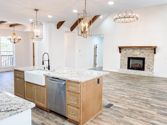 kitchen with a fireplace, light wood finished floors, stainless steel dishwasher, open floor plan, and a sink