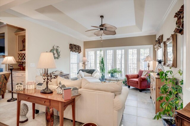 living room featuring ceiling fan, light tile patterned floors, a tray ceiling, and a healthy amount of sunlight