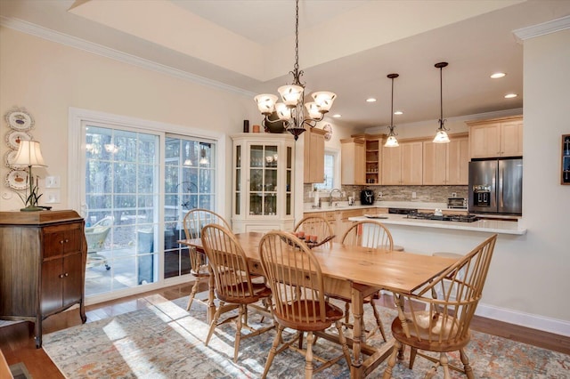 dining room with a raised ceiling, sink, dark hardwood / wood-style flooring, ornamental molding, and a chandelier