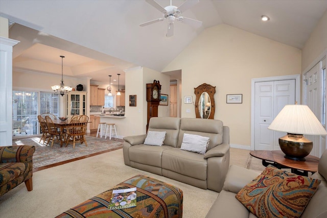 living room with ceiling fan with notable chandelier, light colored carpet, and lofted ceiling