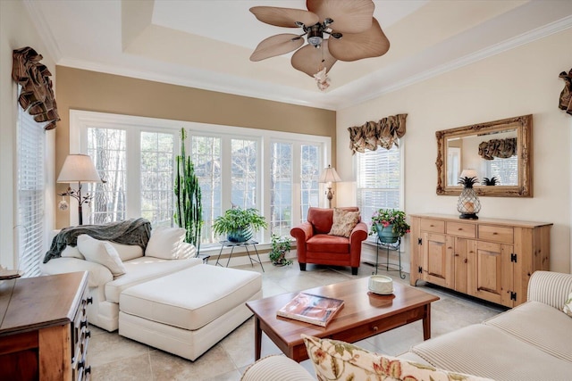 living room featuring ceiling fan, a tray ceiling, ornamental molding, and light tile patterned flooring