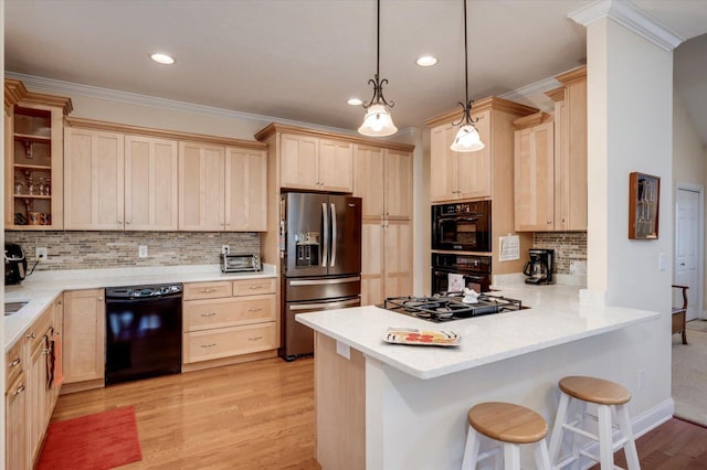 kitchen with kitchen peninsula, pendant lighting, tasteful backsplash, black appliances, and a breakfast bar area