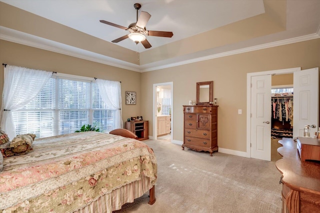 carpeted bedroom with ensuite bathroom, a walk in closet, a closet, ceiling fan, and a tray ceiling