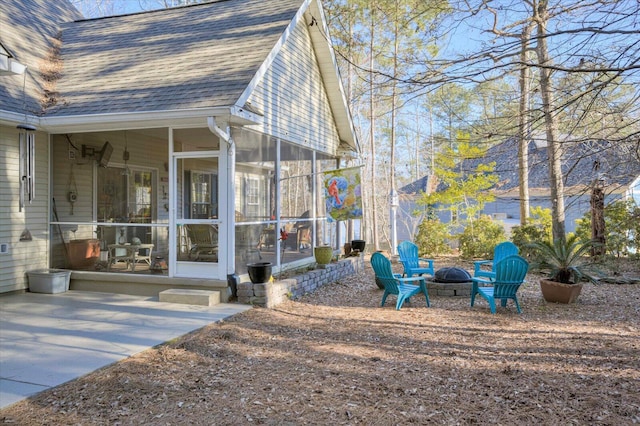 view of side of property featuring a sunroom, an outdoor fire pit, and a patio area