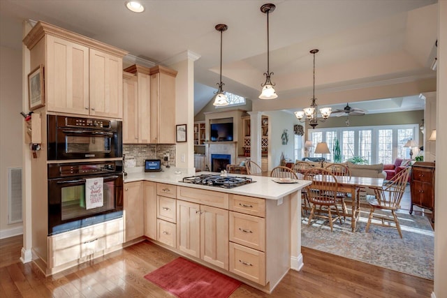 kitchen featuring kitchen peninsula, pendant lighting, black double oven, and stainless steel gas cooktop