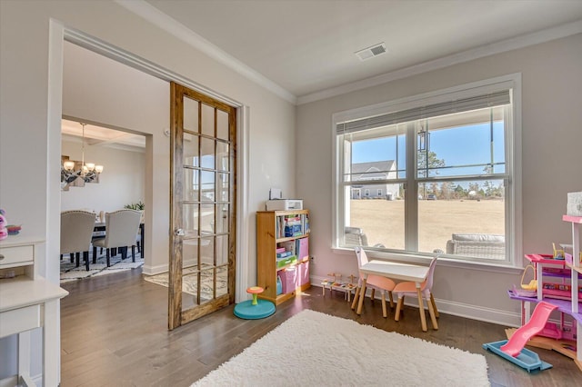 playroom with dark hardwood / wood-style flooring, crown molding, and an inviting chandelier