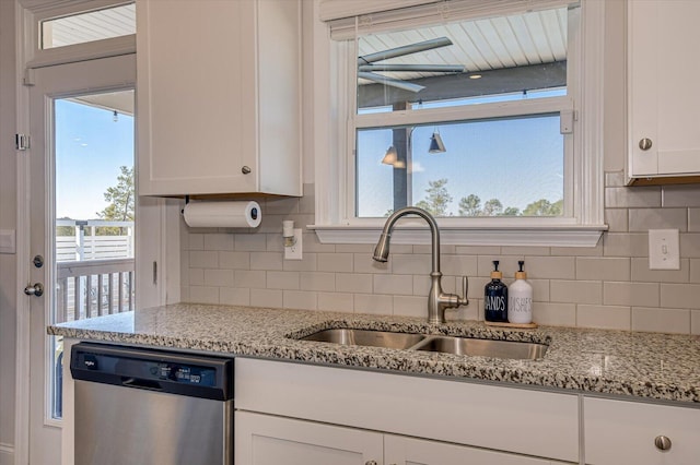 kitchen featuring stainless steel dishwasher, decorative backsplash, white cabinetry, and sink