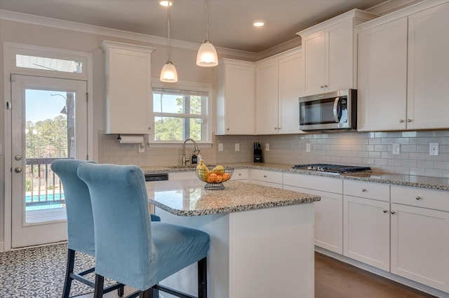 kitchen featuring white cabinets, backsplash, a center island, and stainless steel appliances