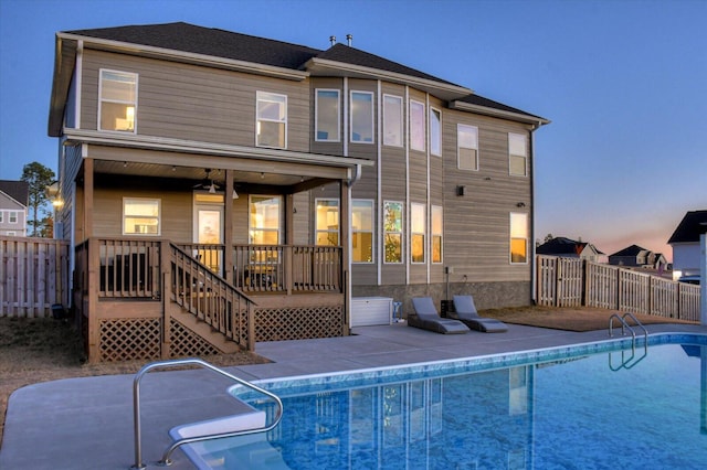 back house at dusk featuring a fenced in pool, ceiling fan, and a patio area