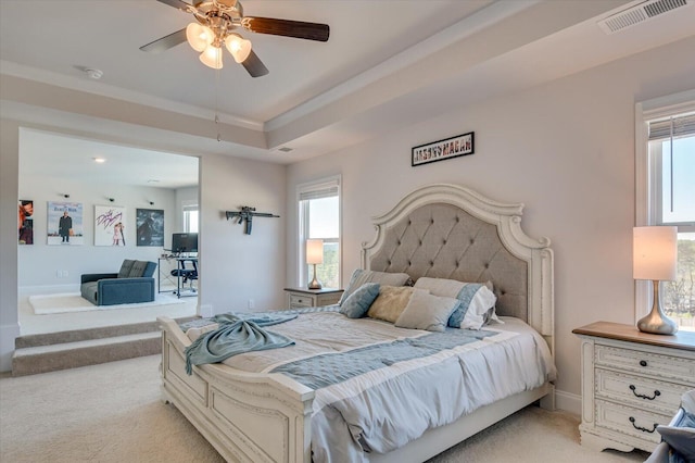 carpeted bedroom with a raised ceiling and ceiling fan