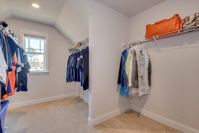 walk in closet featuring light carpet and lofted ceiling