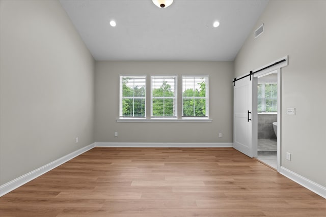 651 Moose Club Rd, Thomson, GA 30824 - unfurnished bedroom featuring a barn door, lofted ceiling, light wood-type flooring, recessed lighting, and baseboards