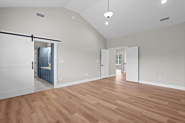 651 Moose Club Rd, Thomson, GA 30824 - unfurnished bedroom featuring high vaulted ceiling, a barn door, light wood-type flooring, recessed lighting, and connected bathroom