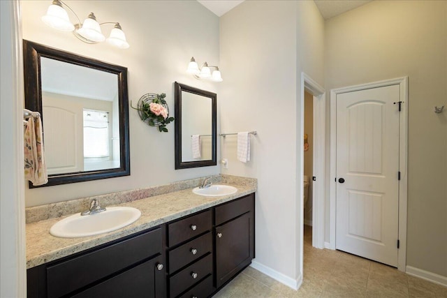 bathroom featuring a sink, baseboards, double vanity, and tile patterned flooring