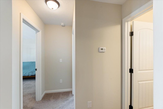 hallway with carpet flooring and baseboards