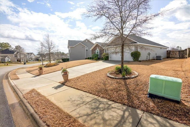 ranch-style house with fence, a residential view, concrete driveway, central AC unit, and a garage