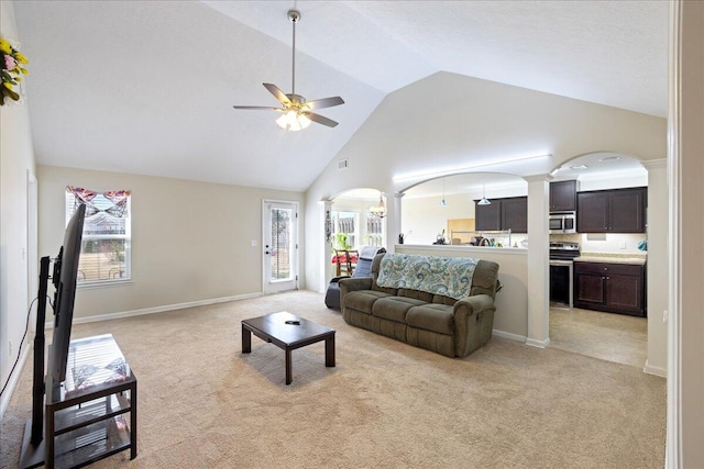 living room featuring light carpet, high vaulted ceiling, arched walkways, ceiling fan, and ornate columns