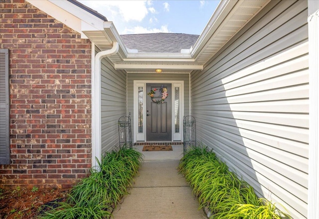 entrance to property with brick siding and roof with shingles