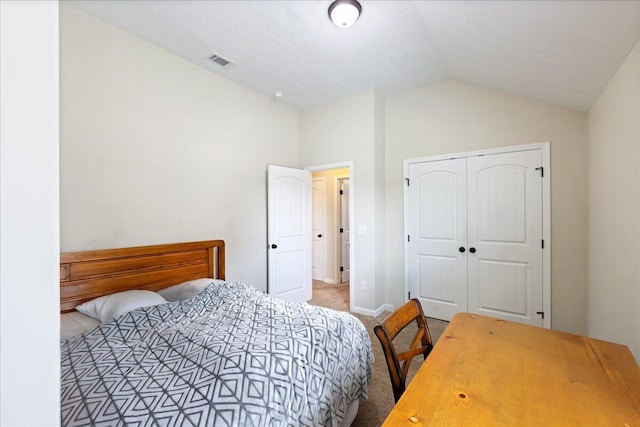 carpeted bedroom featuring a closet, visible vents, baseboards, and vaulted ceiling