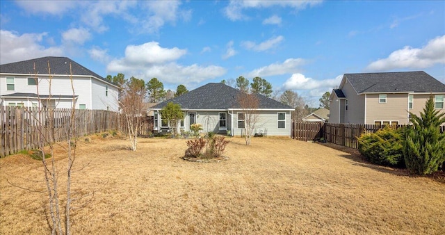 rear view of house featuring a yard and a fenced backyard