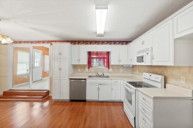 kitchen with white appliances, white cabinetry, and sink