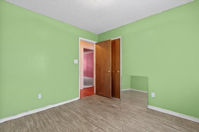 unfurnished room with light hardwood / wood-style floors and a textured ceiling