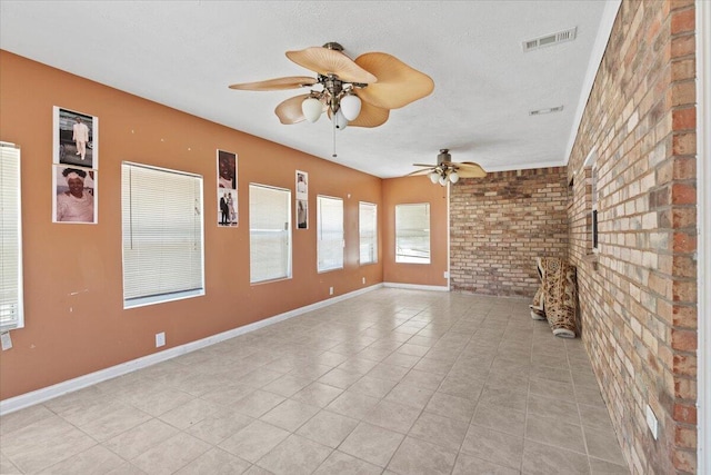 unfurnished living room with ceiling fan, a textured ceiling, and brick wall