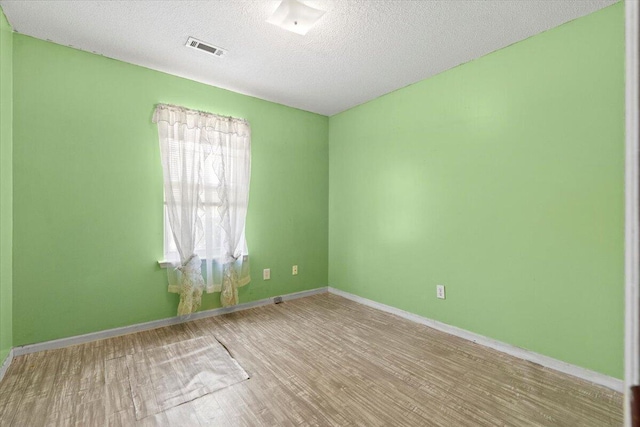 unfurnished room with light wood-type flooring and a textured ceiling