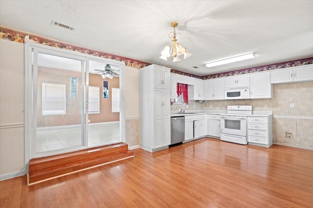 kitchen featuring white cabinets, hanging light fixtures, white appliances, and light wood-type flooring