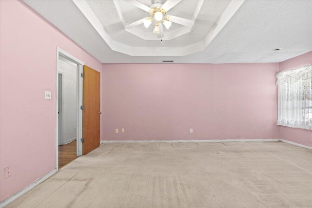 carpeted empty room featuring ceiling fan, a textured ceiling, and a tray ceiling