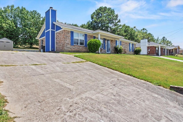 single story home featuring a storage shed and a front lawn