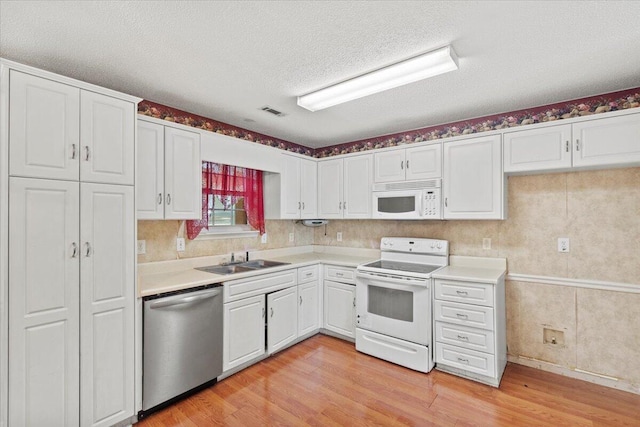 kitchen with white appliances, white cabinets, sink, a textured ceiling, and light hardwood / wood-style floors