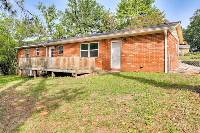 rear view of house featuring brick siding, a deck, and a yard