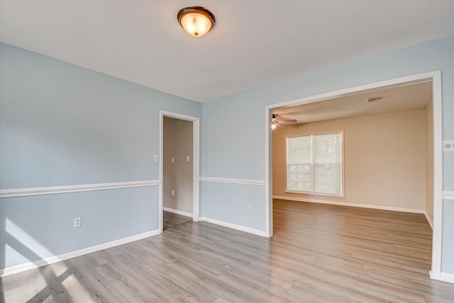 spare room with light wood-style floors, ceiling fan, and baseboards