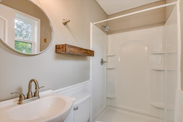 bathroom featuring a sink, a stall shower, and toilet