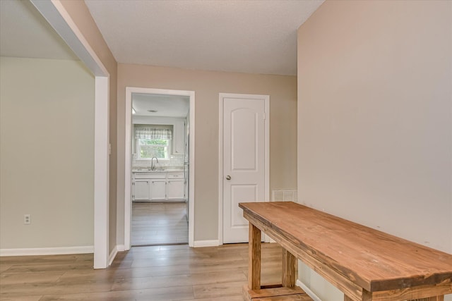 mudroom with a sink, light wood finished floors, and baseboards