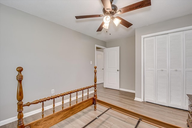 bedroom with light wood finished floors, baseboards, a closet, and a ceiling fan