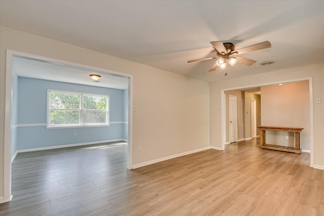 spare room featuring light wood-style floors, a ceiling fan, and baseboards
