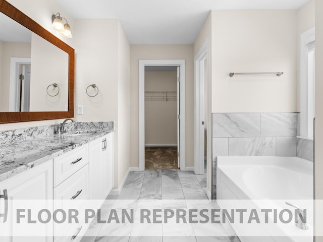 full bathroom featuring marble finish floor, a spacious closet, a garden tub, and vanity