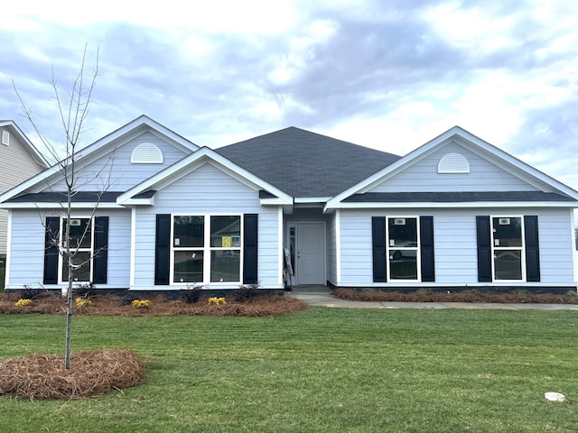 ranch-style home with roof with shingles and a front lawn