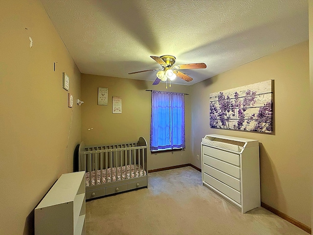 bedroom with a textured ceiling, ceiling fan, light colored carpet, and baseboards