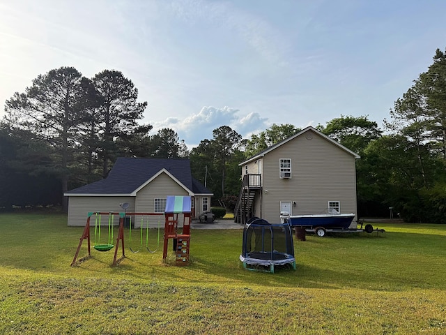 rear view of property with a yard, a trampoline, a playground, and stairway