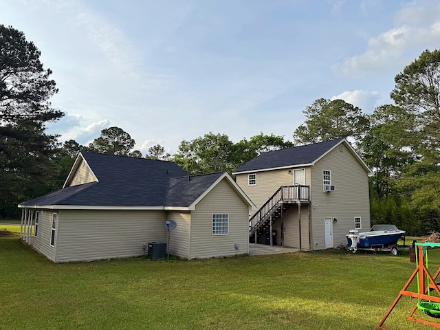 rear view of house with a yard, cooling unit, and a playground