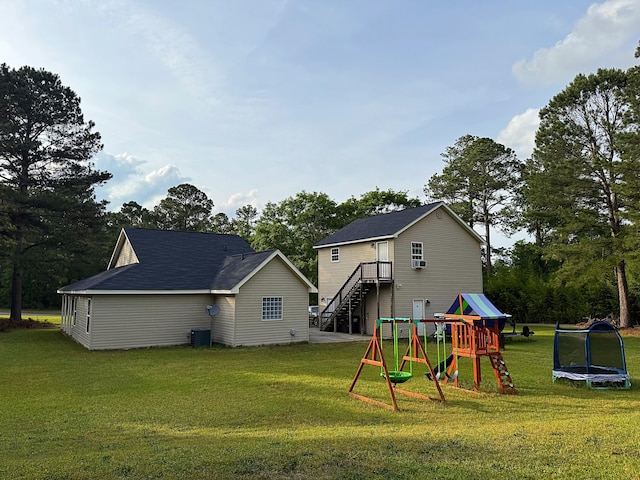 rear view of house with a trampoline, a playground, and a lawn