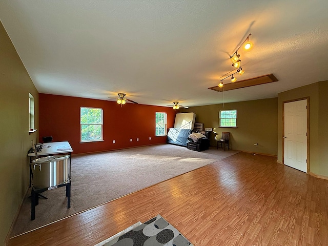 living area featuring a wealth of natural light, wood finished floors, ceiling fan, and baseboards