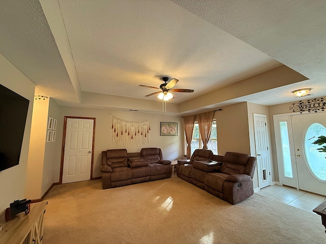living room featuring light colored carpet, ceiling fan, baseboards, a raised ceiling, and a textured ceiling