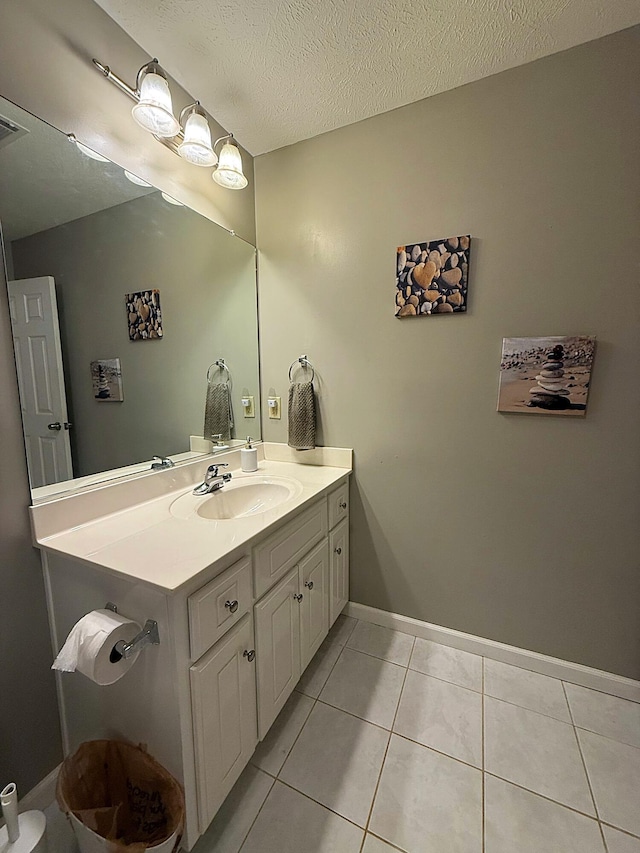 bathroom with tile patterned floors, a textured ceiling, vanity, and baseboards