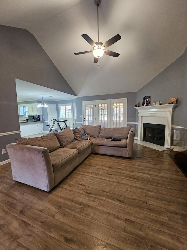 living room featuring a fireplace with flush hearth, dark wood-style flooring, high vaulted ceiling, and ceiling fan with notable chandelier